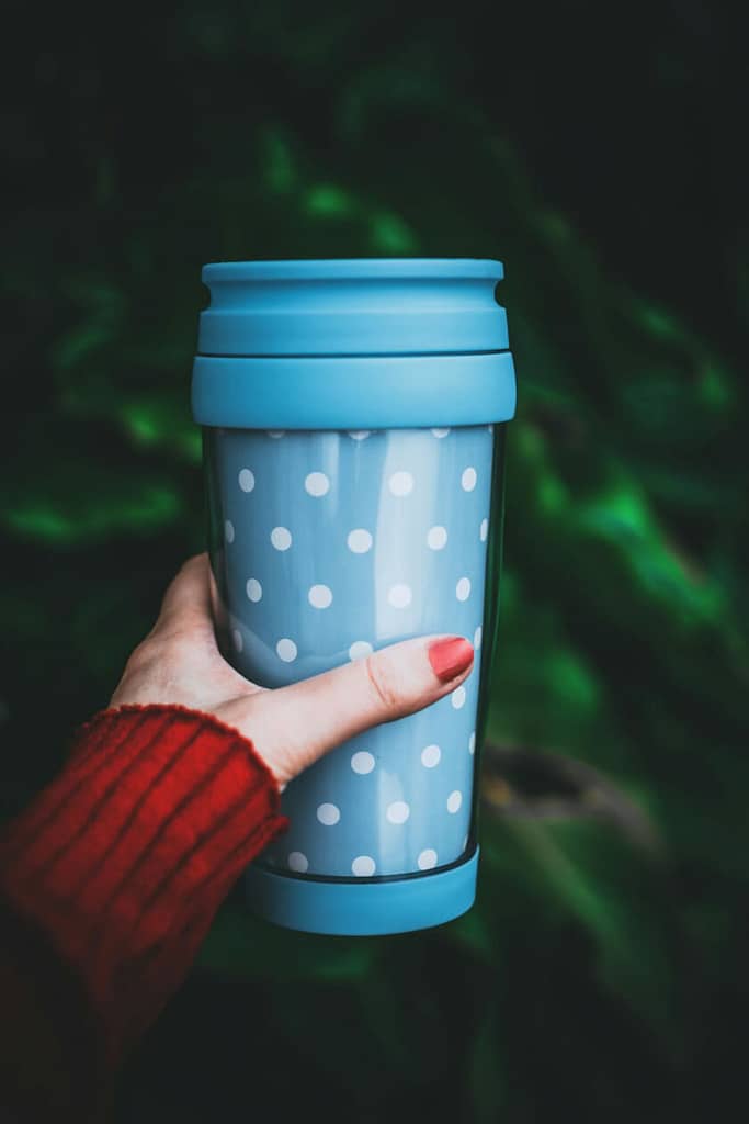 A hand holding a tumbler, a useful tea accessory for tea drinkers on the go.