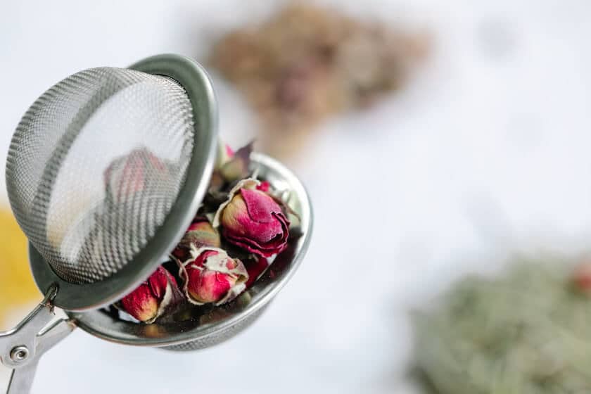 A tea ball, a tea accessory used as an infuser, holding dried flowers.