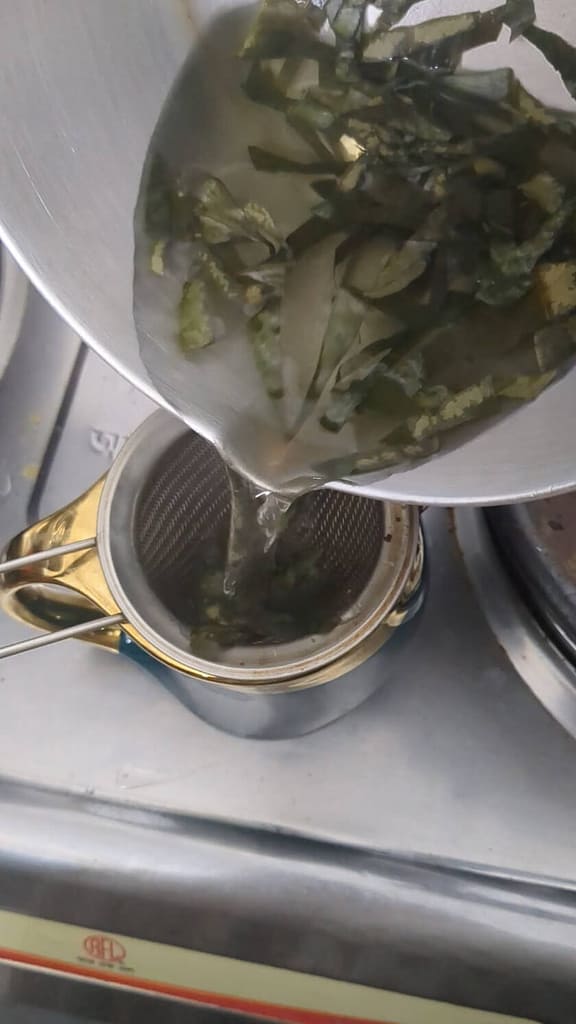 Final step in how to make tea from soursop leaves: pour tea over strainer and enjoy
