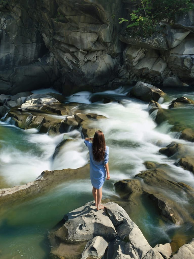 Girl in nature admiring flow of water; flow of water is similar to wu-wei in taoism